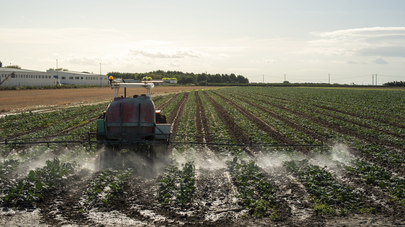 En traktor spreder pesticider på en mark