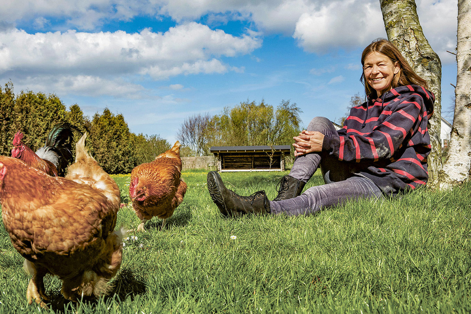 Eva Bøtker sidder i græsset med en folk høns.