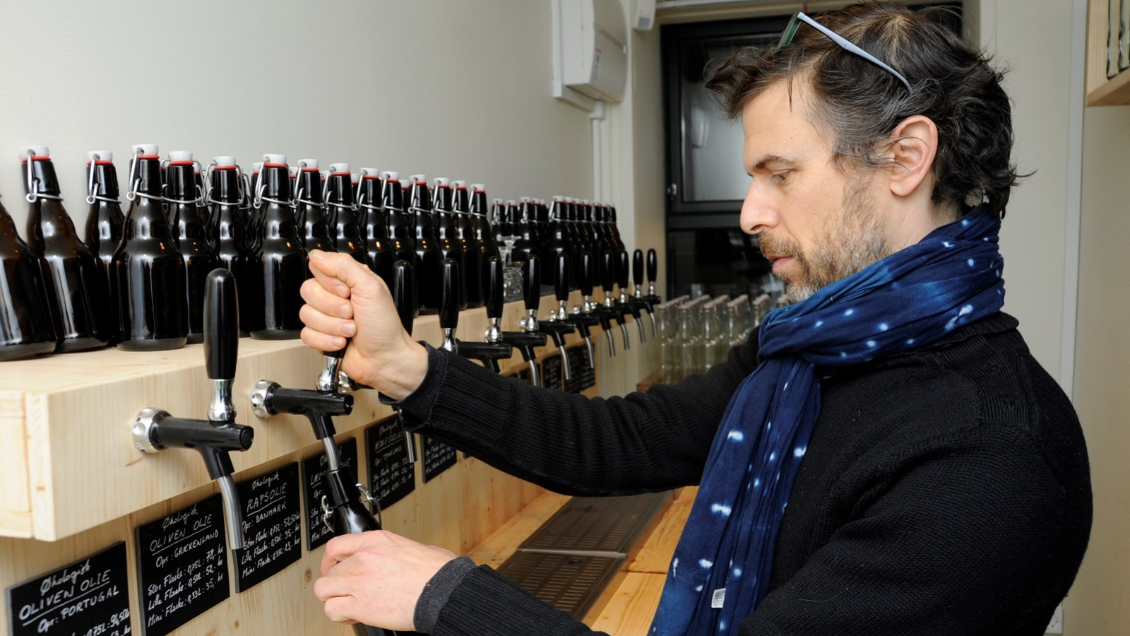 Frédéric Hamburger tapper olie på genbrugsflaske i LØS Market.