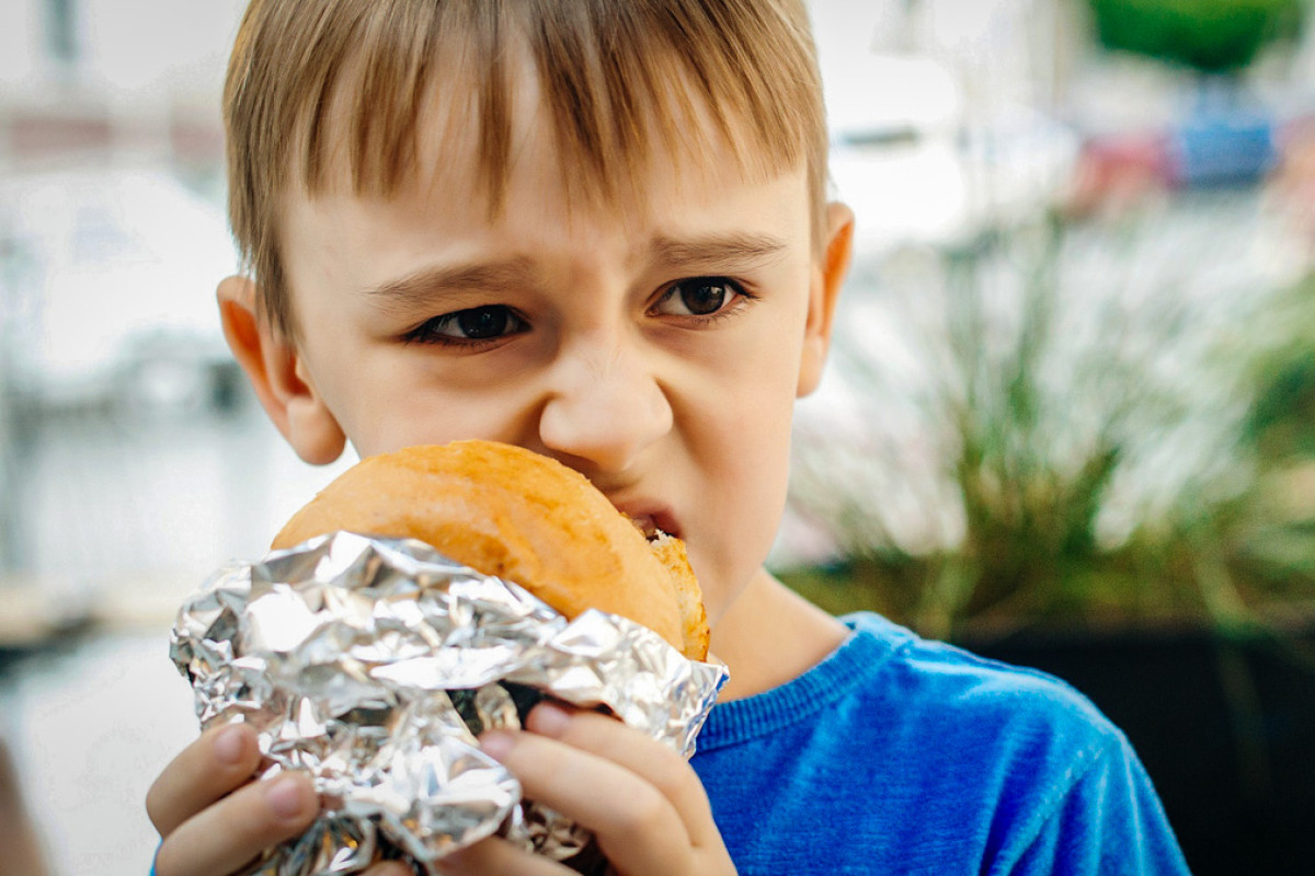 En dreng ser utilfreds ud, mens han spiser sin madpakke